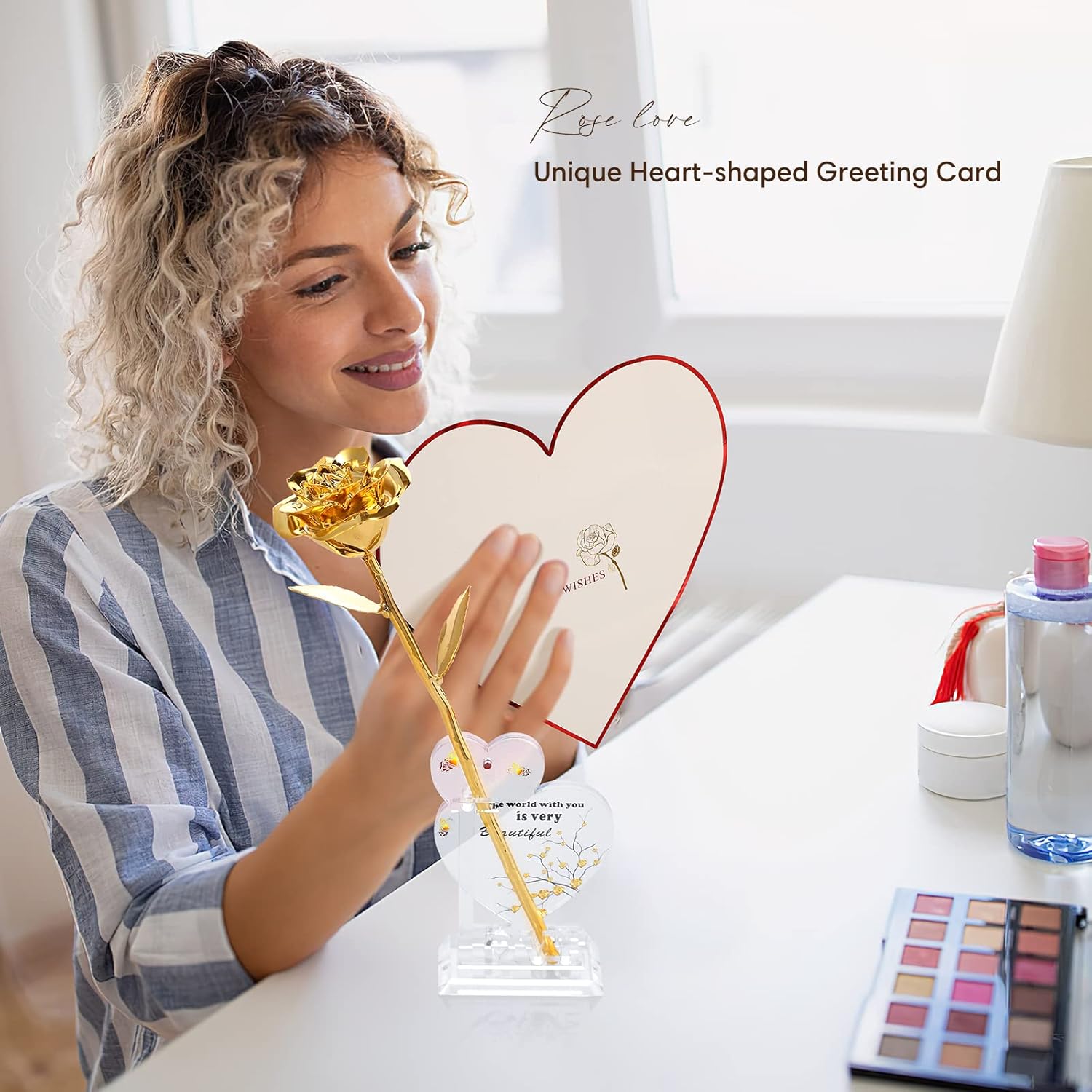 Woman holding a heart-shaped greeting card with a gold pen, surrounded by makeup items on a table.